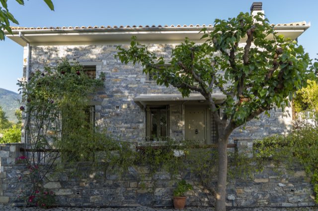 The villa&rsquo;s stone front behind the garden tree