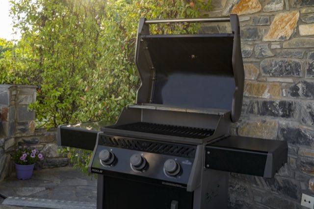 The gas barbecue against the patio&rsquo;s stone wall